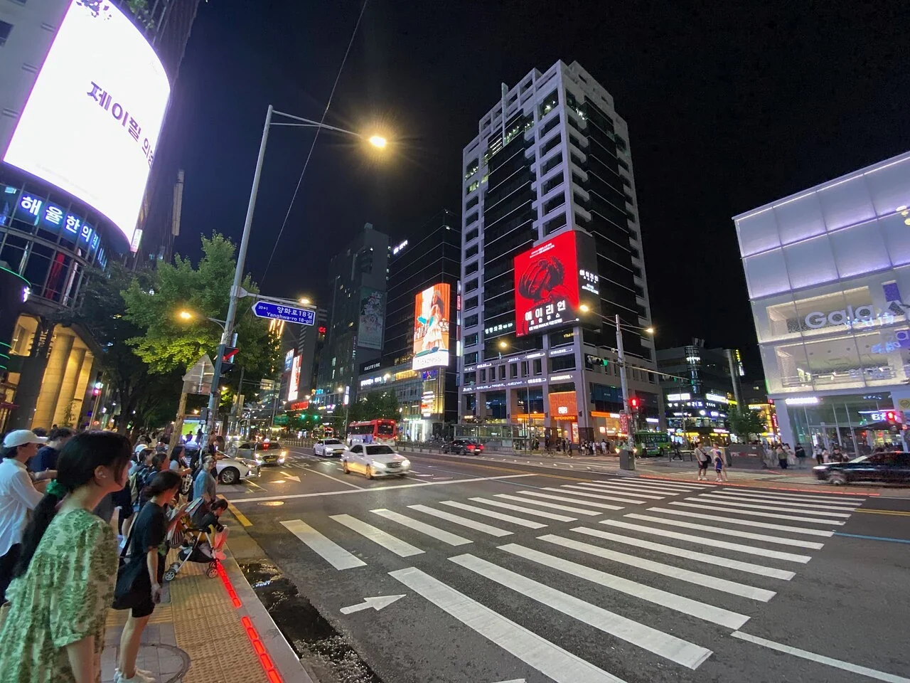 Ein Zebrastreifen und beleuchtete Geschäfte in Hongdae bei Nacht