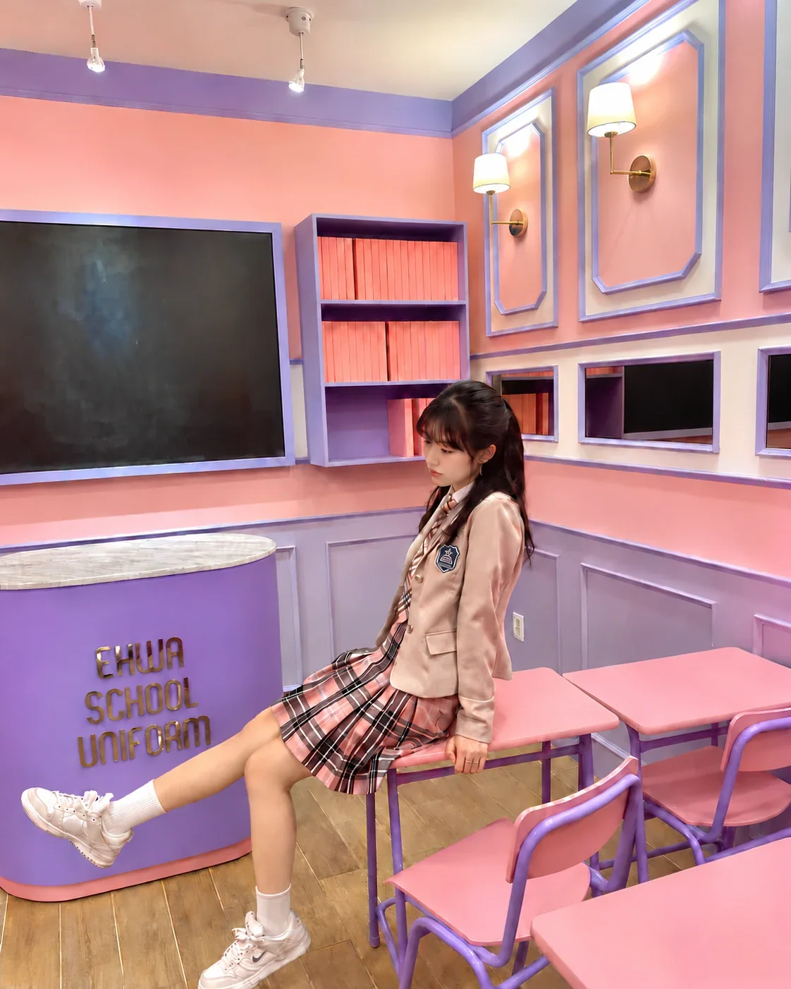 Una visitatrice in uniforme scolastica seduta nell’area fotografica con aula rosa di Ehwa